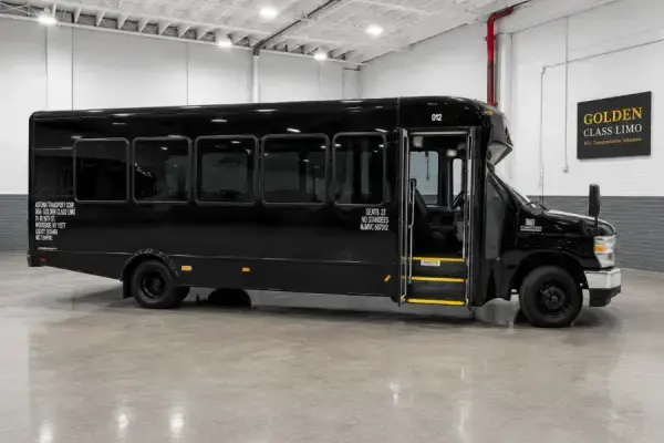 Black 23-passenger mini bus, unit 012, photographed in the Golden Class Limo garage with the door open
