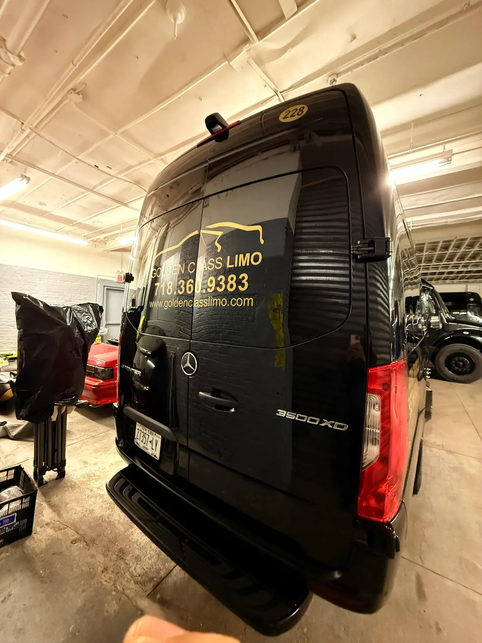 Rear of the Luxury Sprinter in the Golden Class Limo garage, the gold wordmark across the door