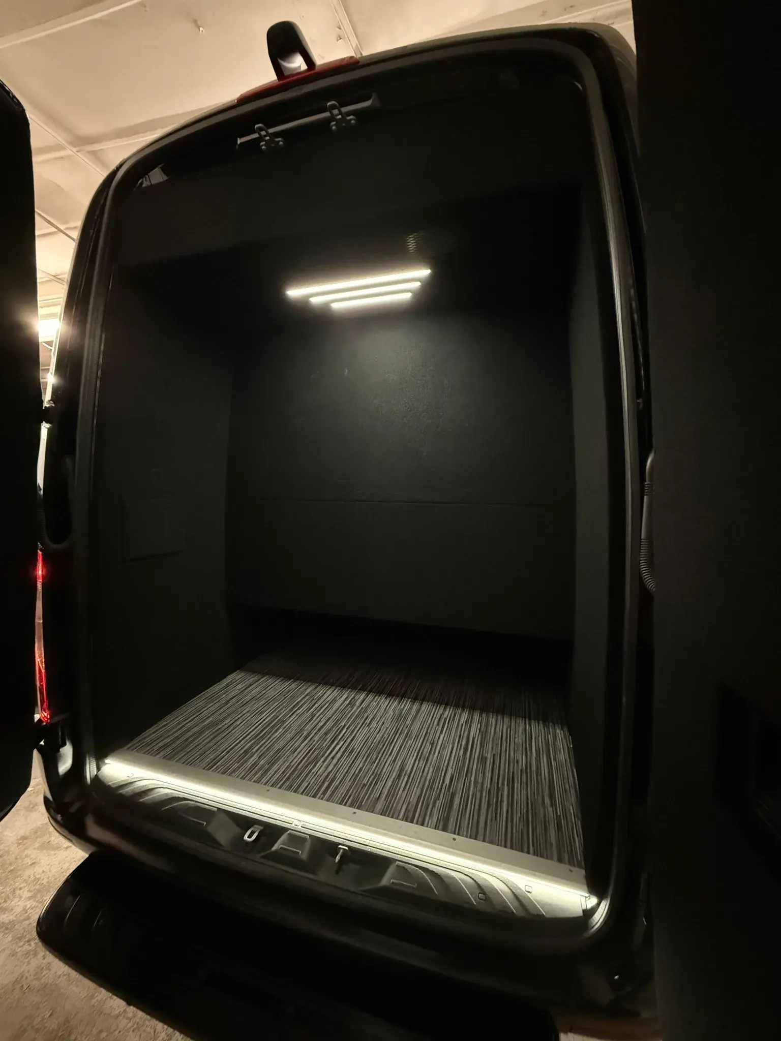 Rear doors open on the Luxury Sprinter, showing the lit luggage bay behind the last row of seats