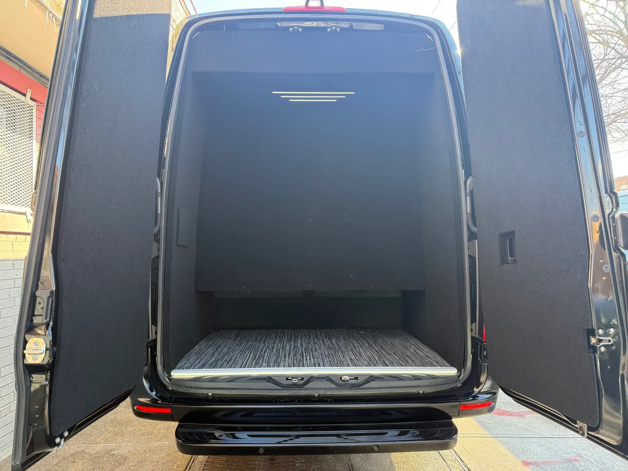 Rear doors open on a Golden Class Limo Sprinter, showing the empty load floor used for luggage