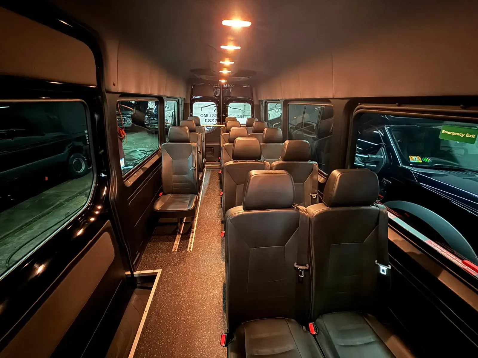 Interior of a Golden Class Limo Sprinter van looking forward from the rear row, the company lettering visible through the windscreen on a van parked alongside
