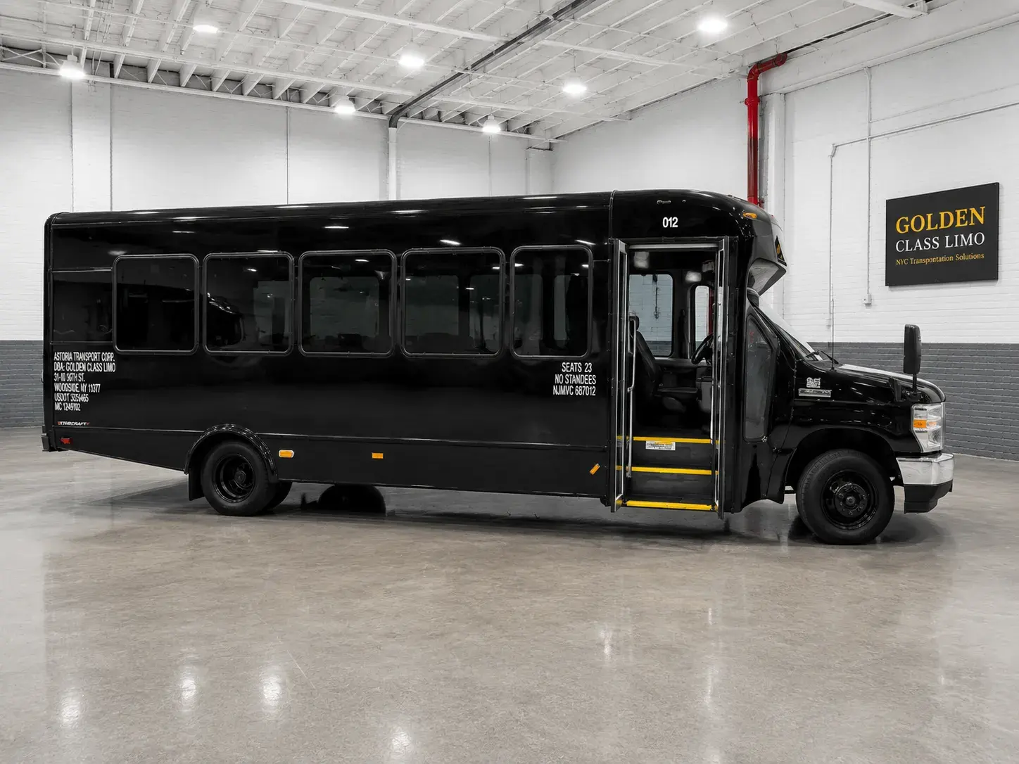 Black 23-passenger mini bus in the Golden Class Limo garage with its passenger door open