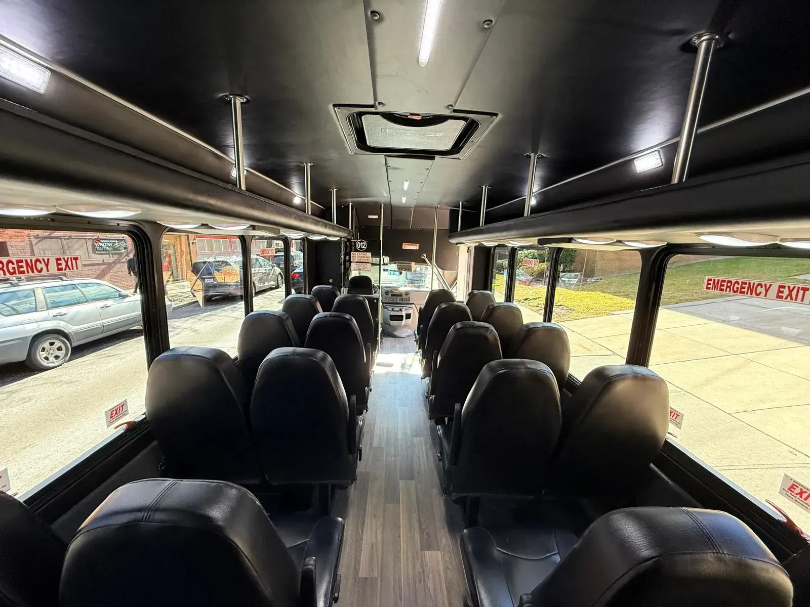 Inside the 23-passenger mini bus, black leather seats either side of a wood-effect aisle