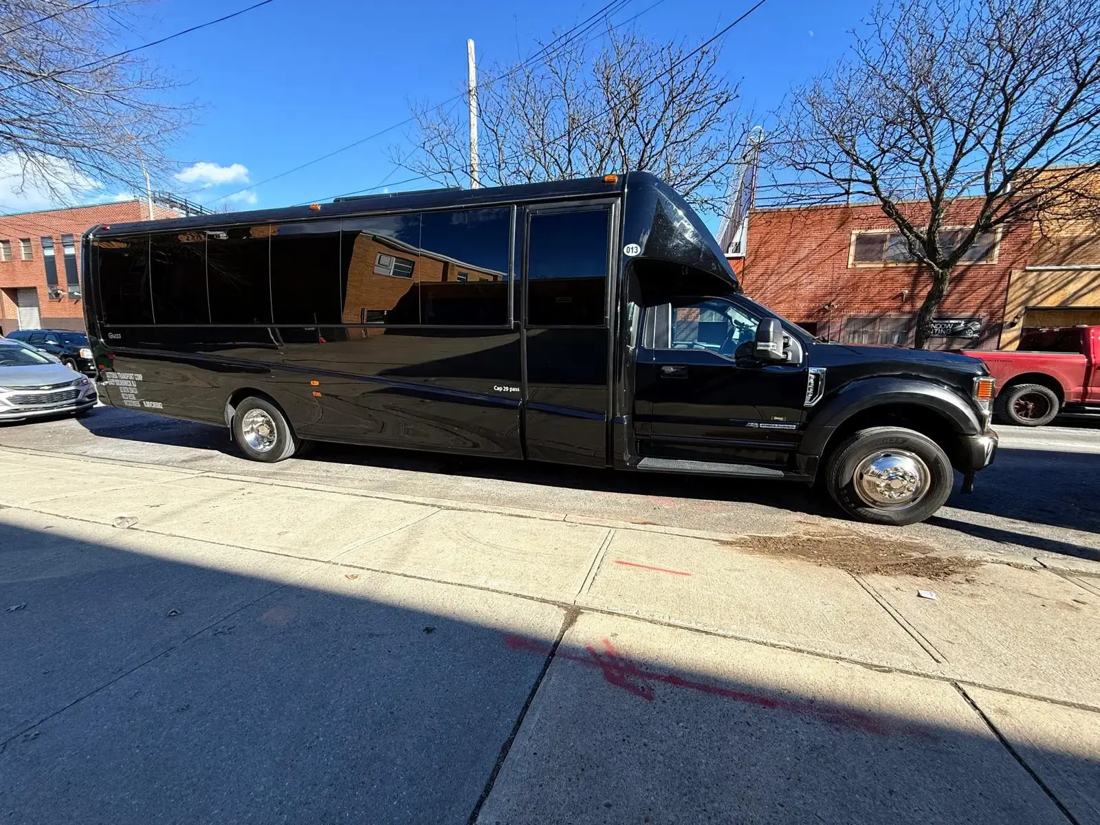 Black 29-passenger mini bus kerbside, its capacity lettered on the body
