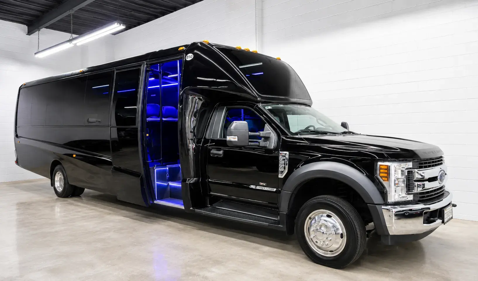 Black 32-passenger mini bus with its door open, ambient lighting visible inside