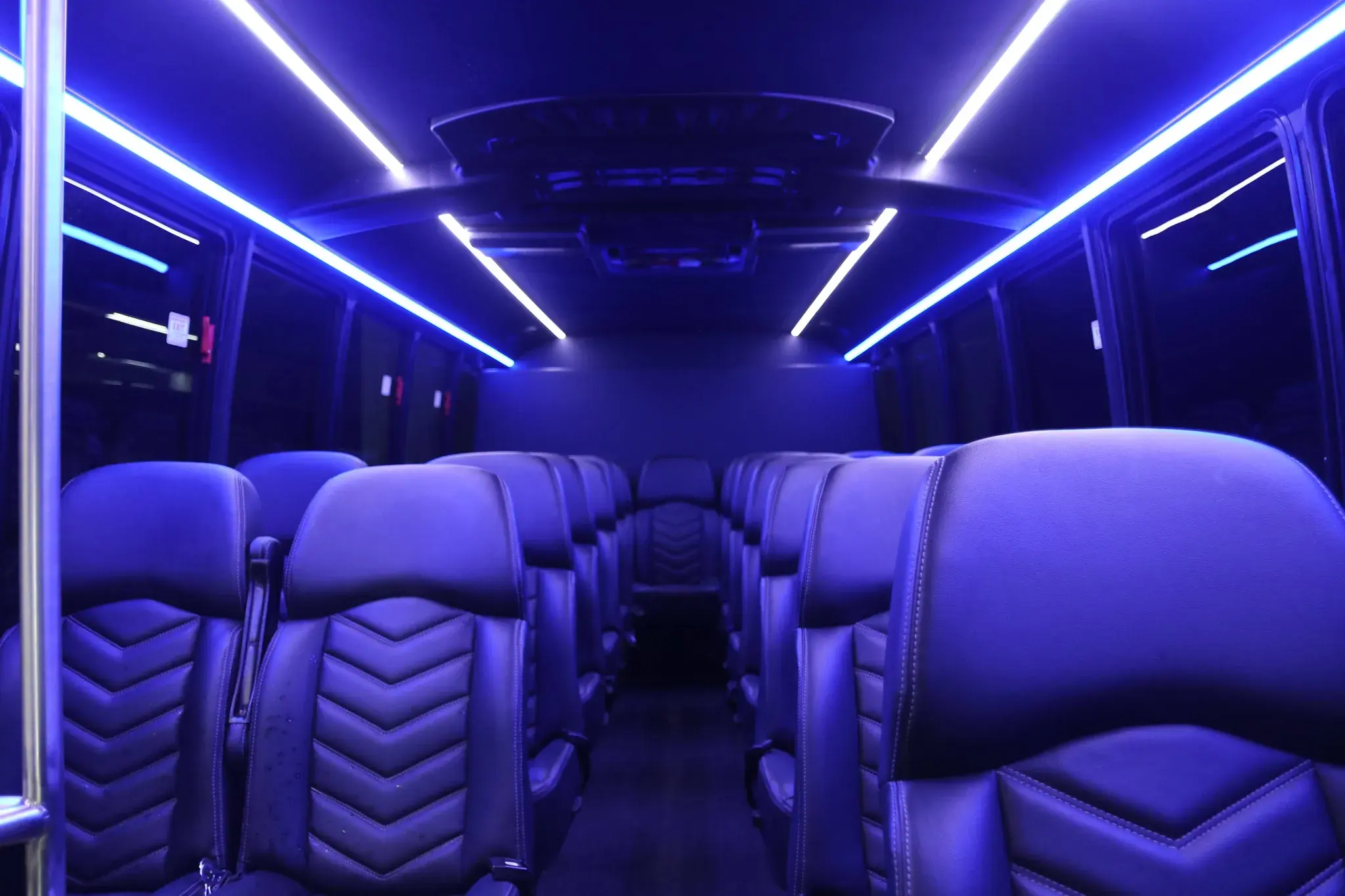 Inside the 32-passenger mini bus, stitched leather seating under blue ambient lighting