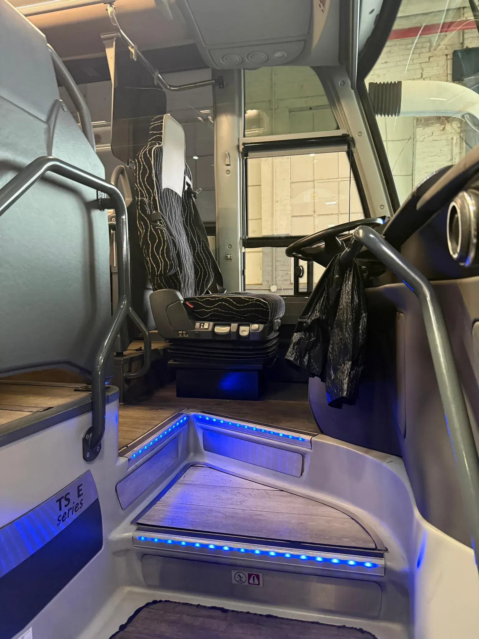 Entry stairwell of the Temsa coach, lit blue, with the driver position beyond