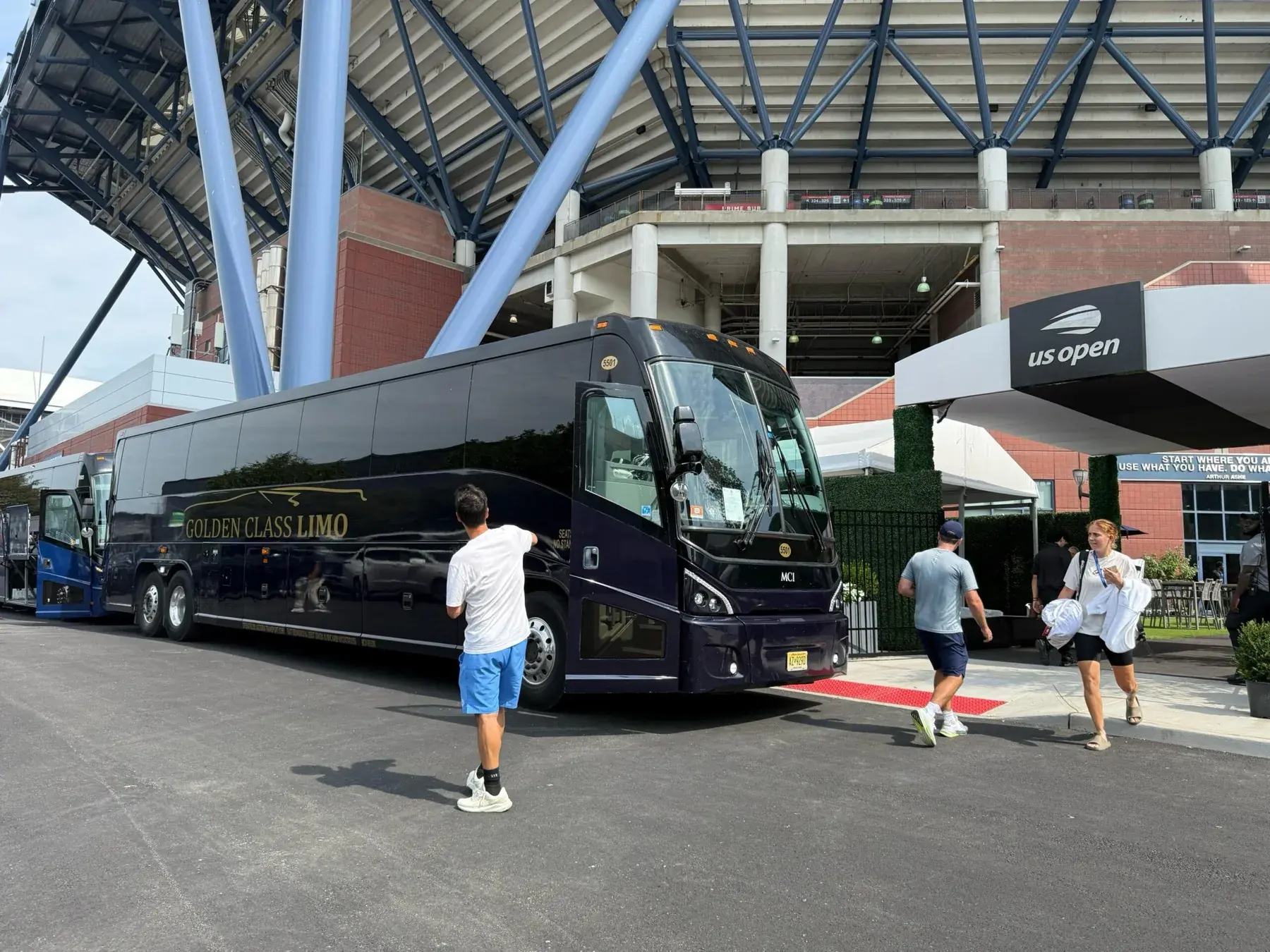 Golden Class Limo 55-passenger motor coach in gold livery parked outside Arthur Ashe Stadium at the US Open
