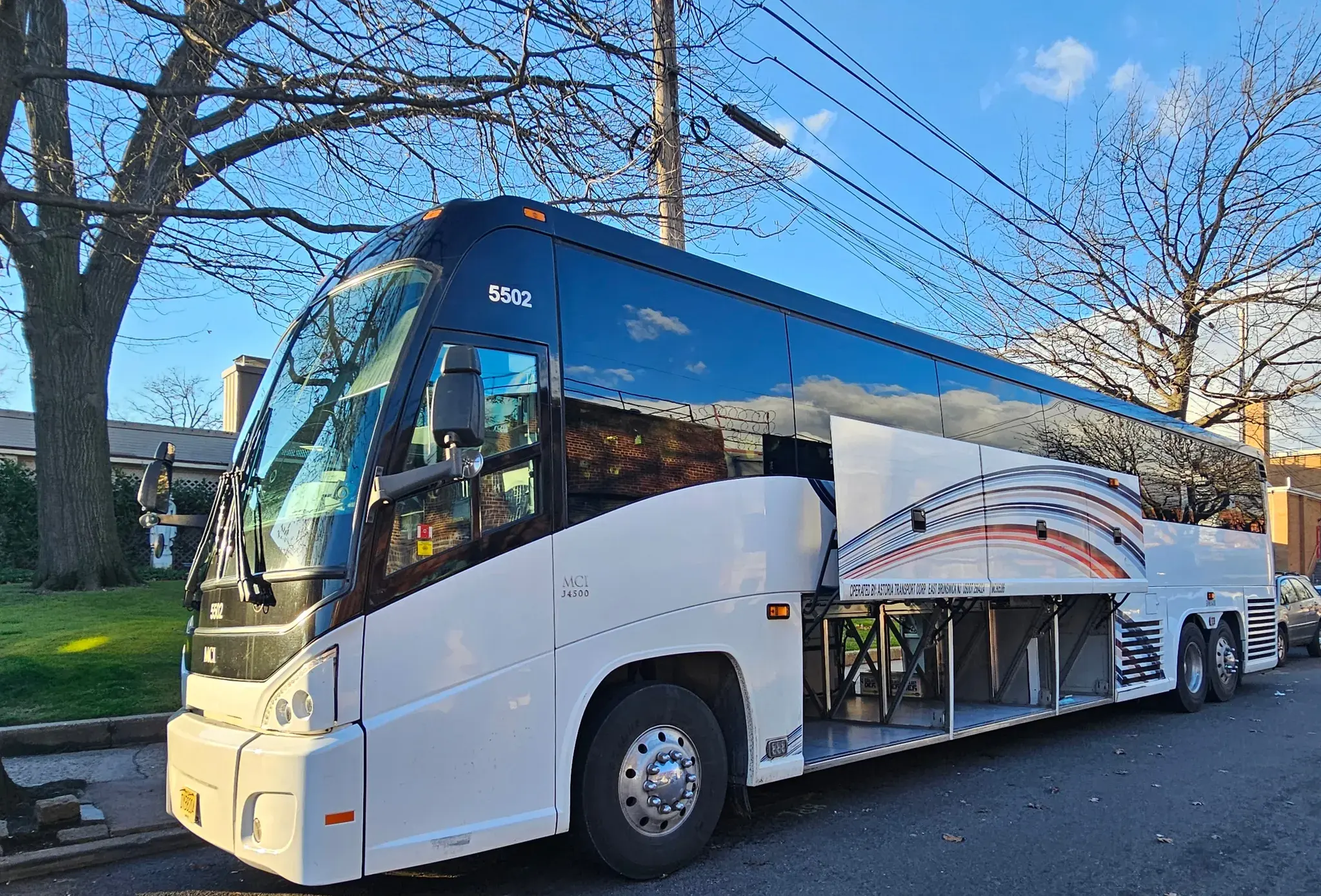 MCI motor coach parked kerbside with its underfloor luggage bays open