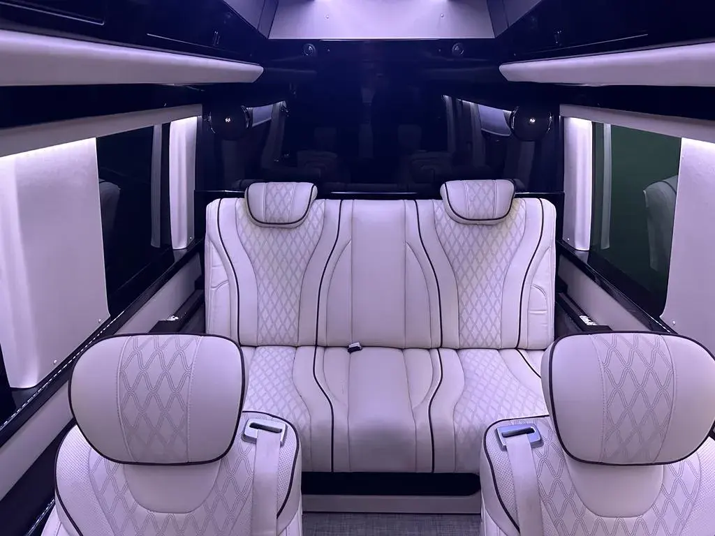 Cream quilted captain chairs and the rear bench inside the Jet Sprinter, privacy shades drawn across the side windows