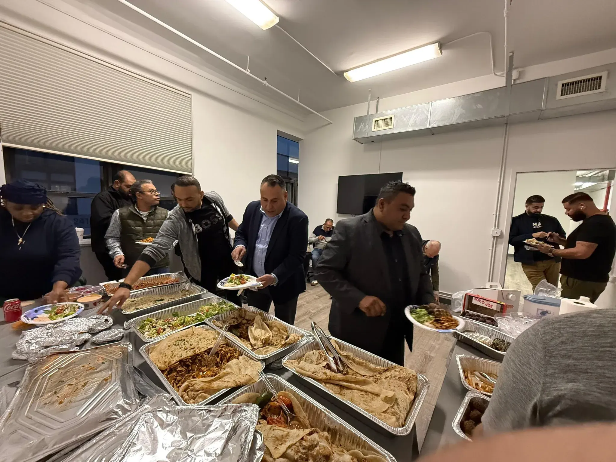Golden Class Limo staff serving themselves from a long buffet of home-style dishes at the office iftar