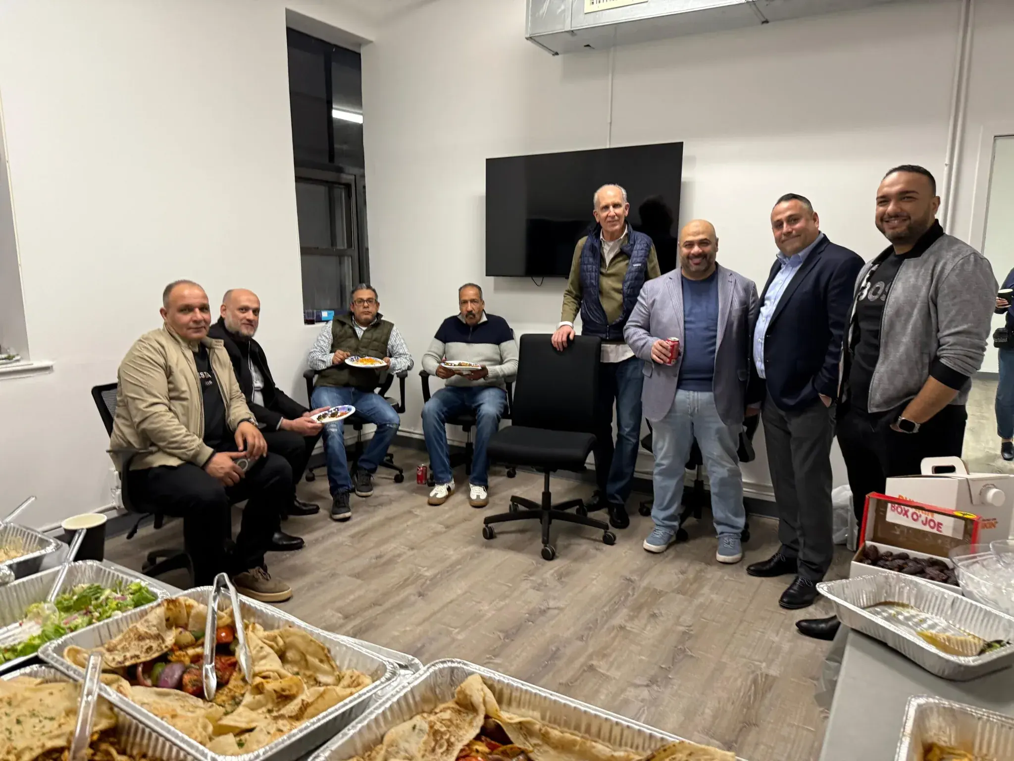Nine members of the Golden Class Limo team gathered with plates at the office iftar