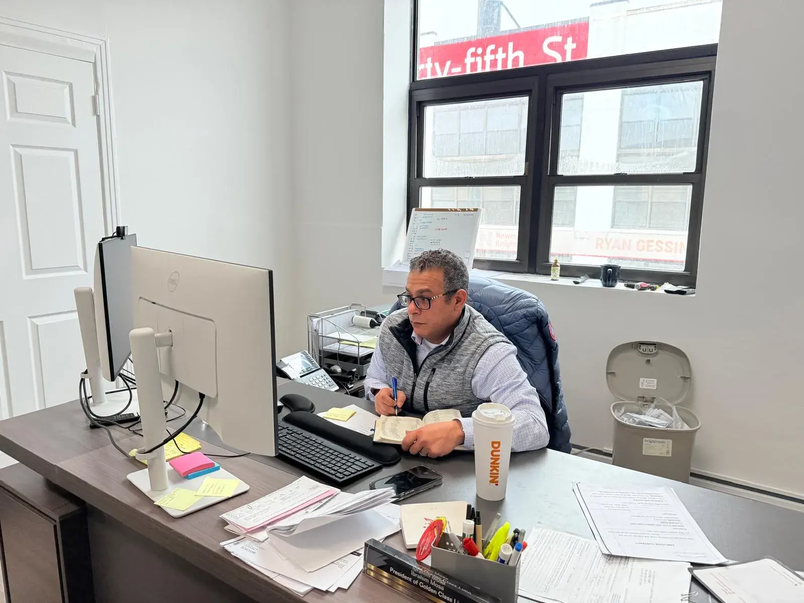 Ibrahim Musa, President of Golden Class Limo, working at his desk beside a window