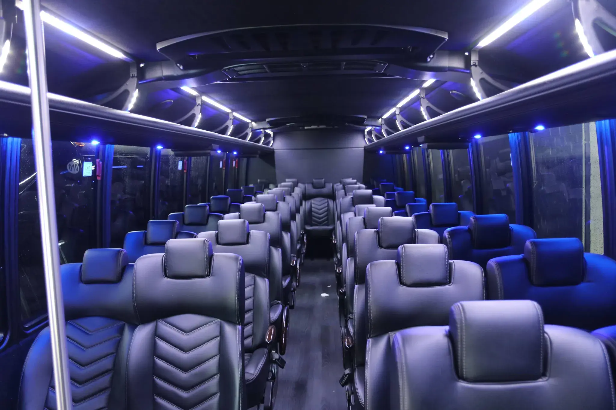 Mini bus cabin on unit 010, high-backed leather seats in rows under blue ambient roof lighting